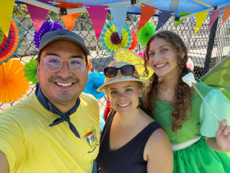 Two Arcora Foundation staff members and the Tooth Fairy stand in front of a brightly colored event tent